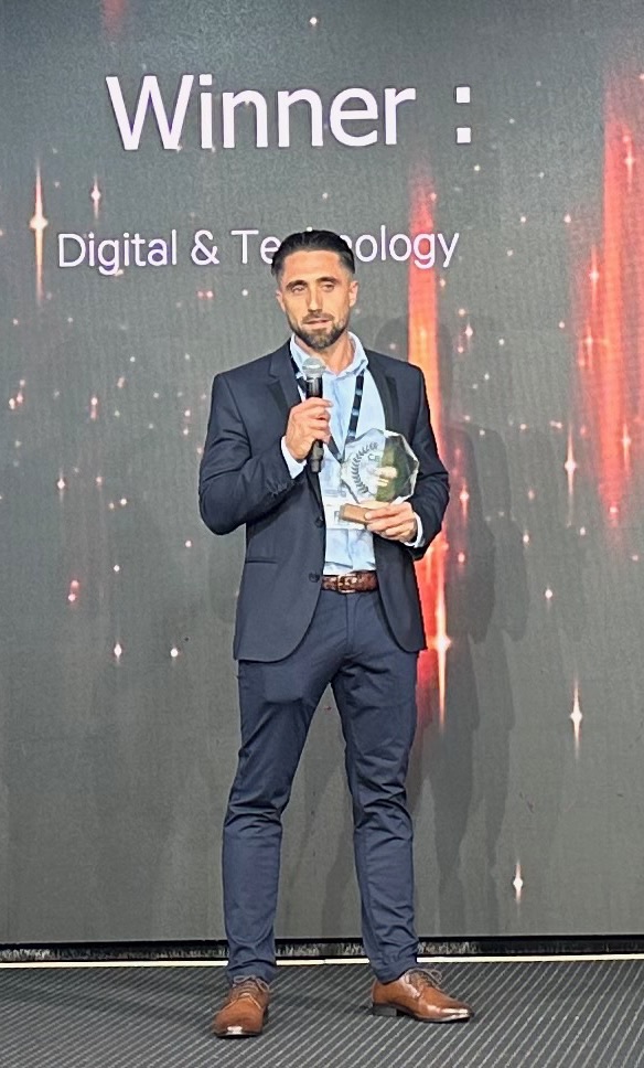 Anthony Ciccomancini au micro, trophée en main, sous l’annonce Winner : Digital & Technology